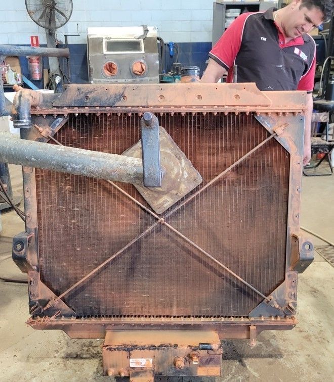 A man is standing behind a rust radiator — Berrimah Radiator Service In Berrimah, NT