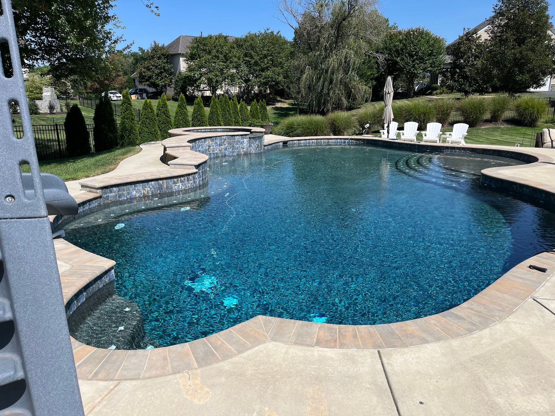 Pool with blue water and stone surround; lounge chairs in the background.