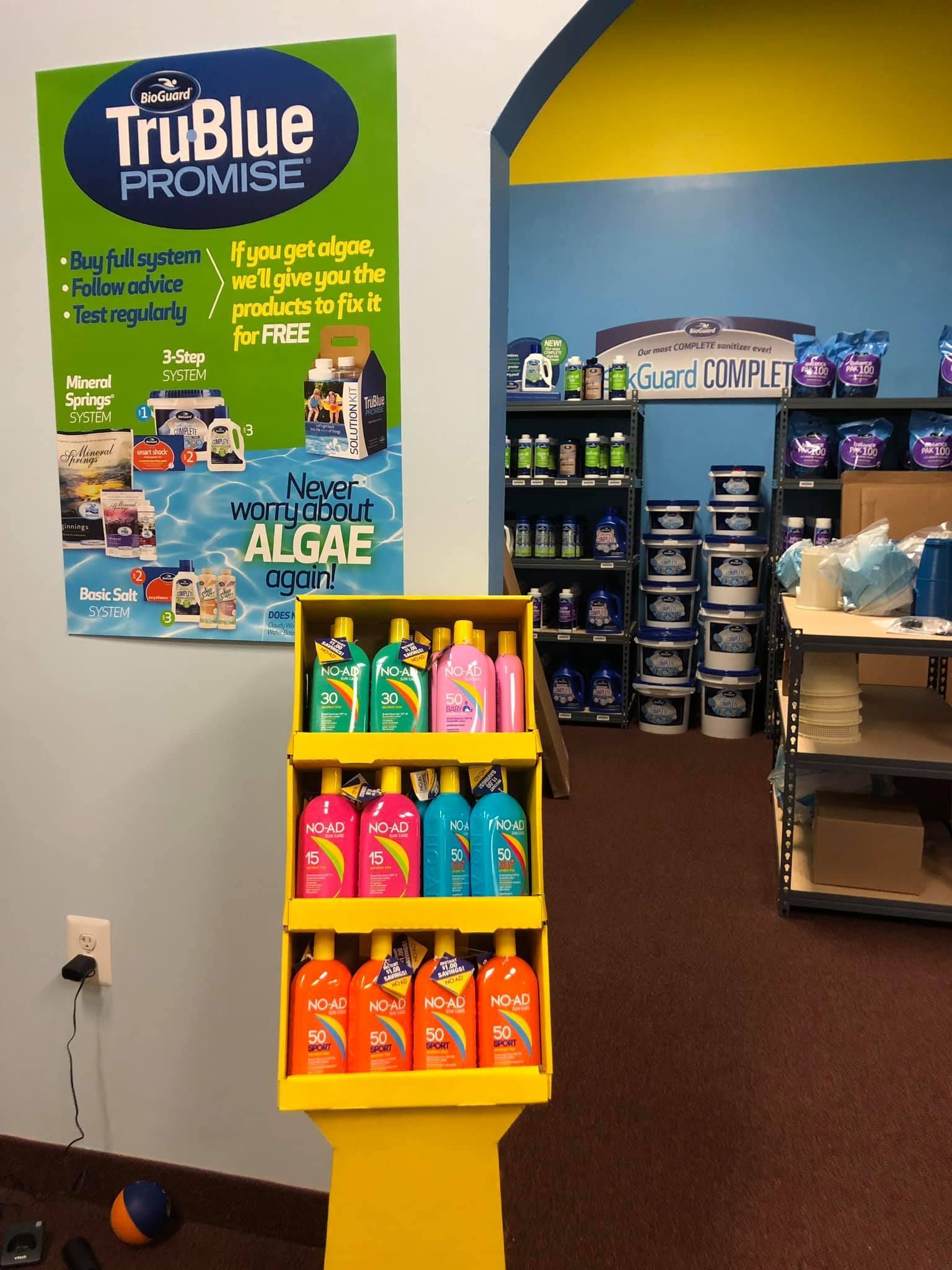Display of colorful pool chemicals inside a store with TruBlue sign promoting algae removal.