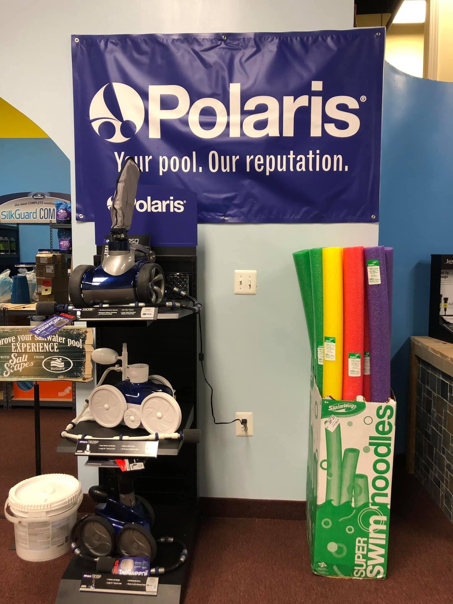 Display of Polaris pool cleaners and swim noodles at a store. Sign says 