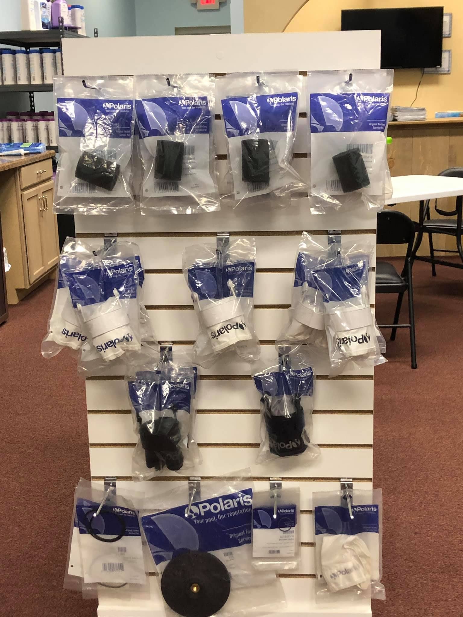 Display rack with various Polaris pool cleaner parts in clear plastic packaging.