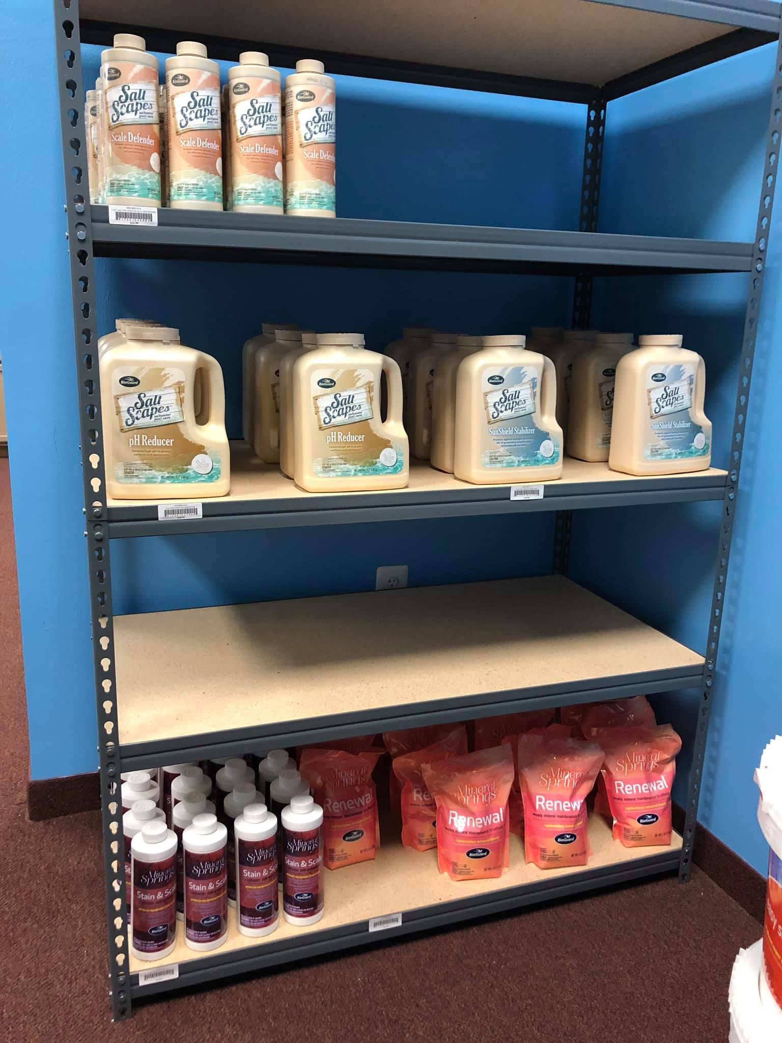 Shelving unit filled with various cleaning product containers. Brown jugs, pink bags, and purple bottles are visible.