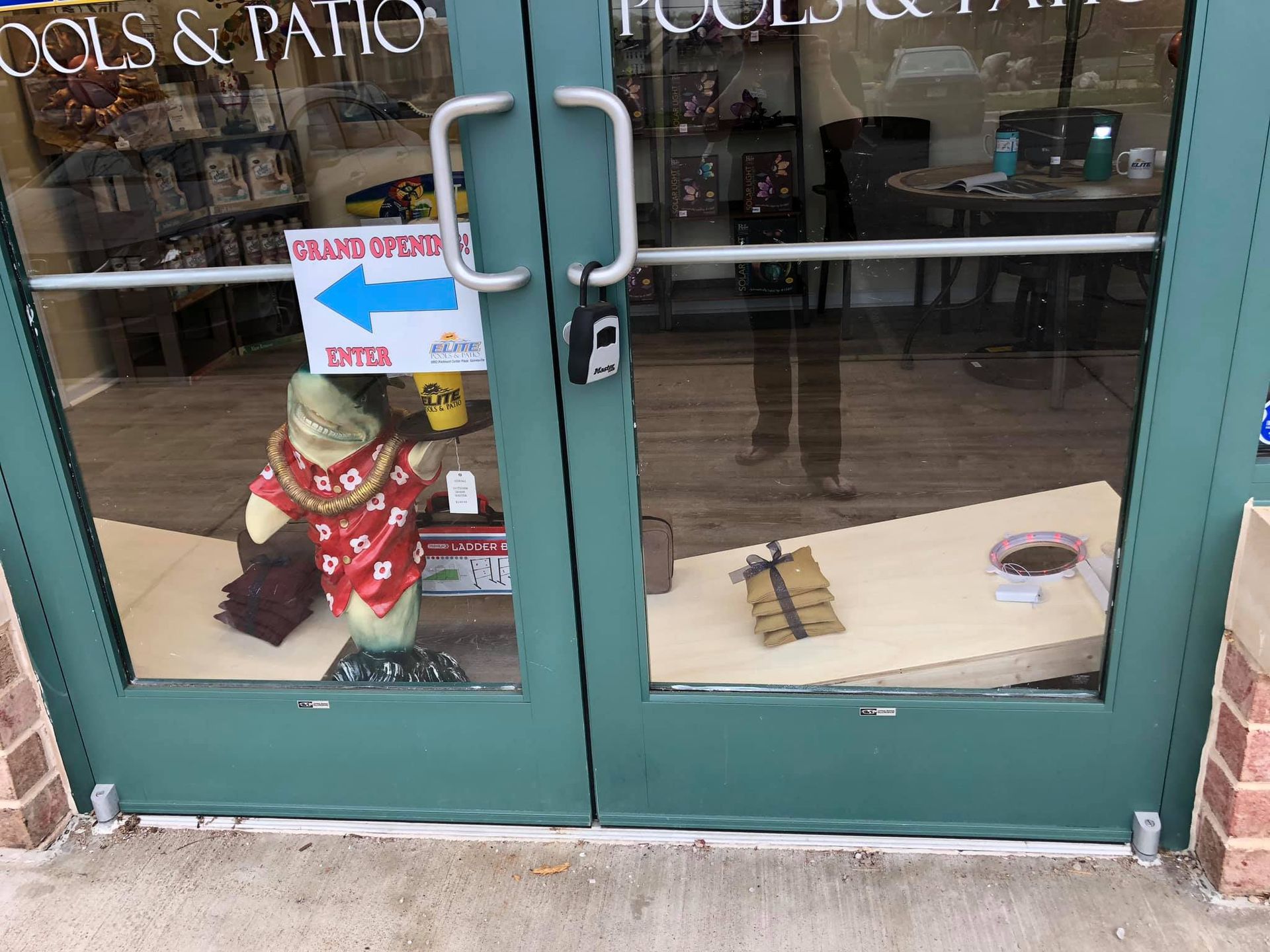 Green glass doors with a sign directing people to enter.