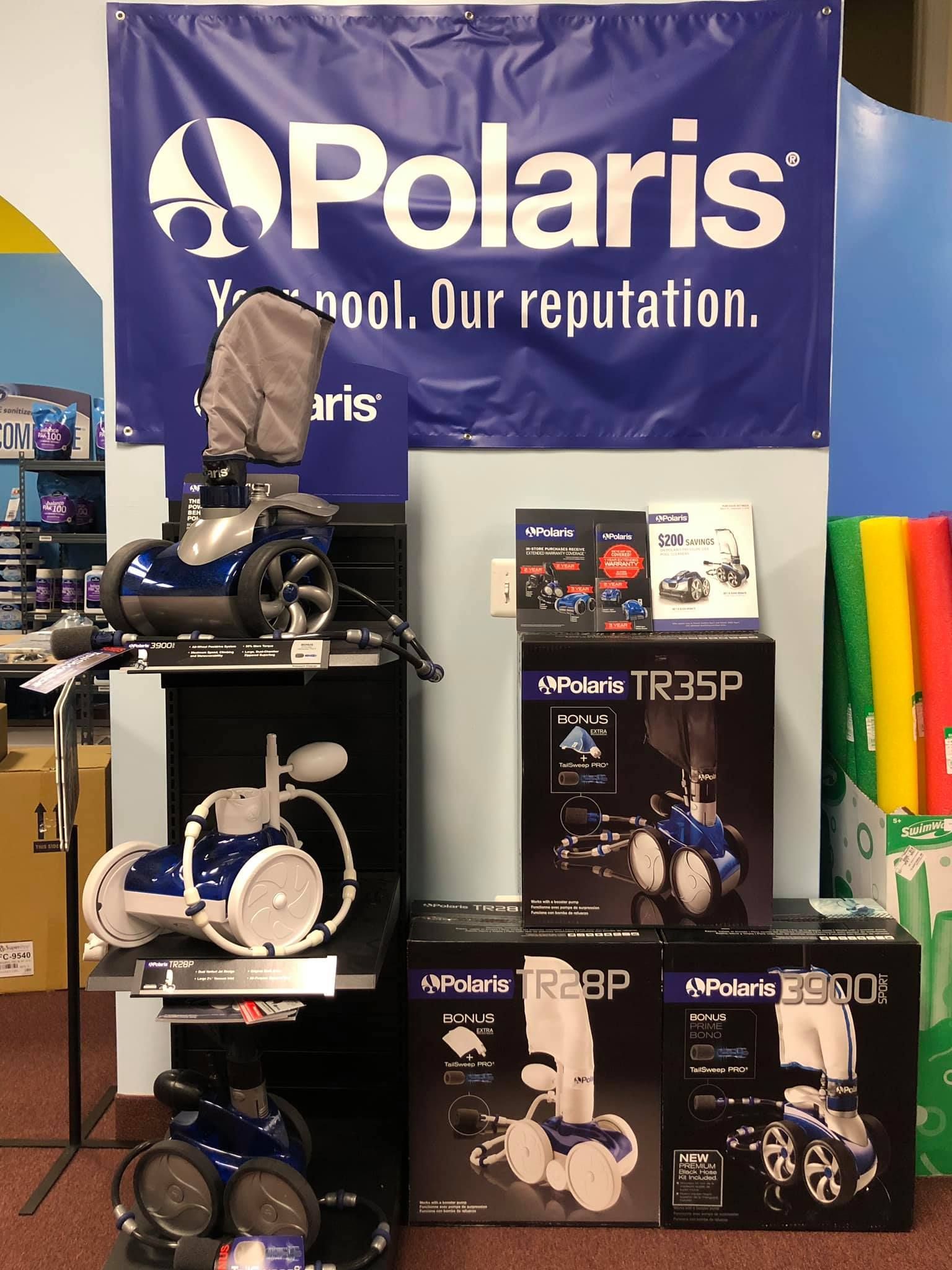 Display of Polaris pool cleaners and accessories in a store setting, with a large blue banner.