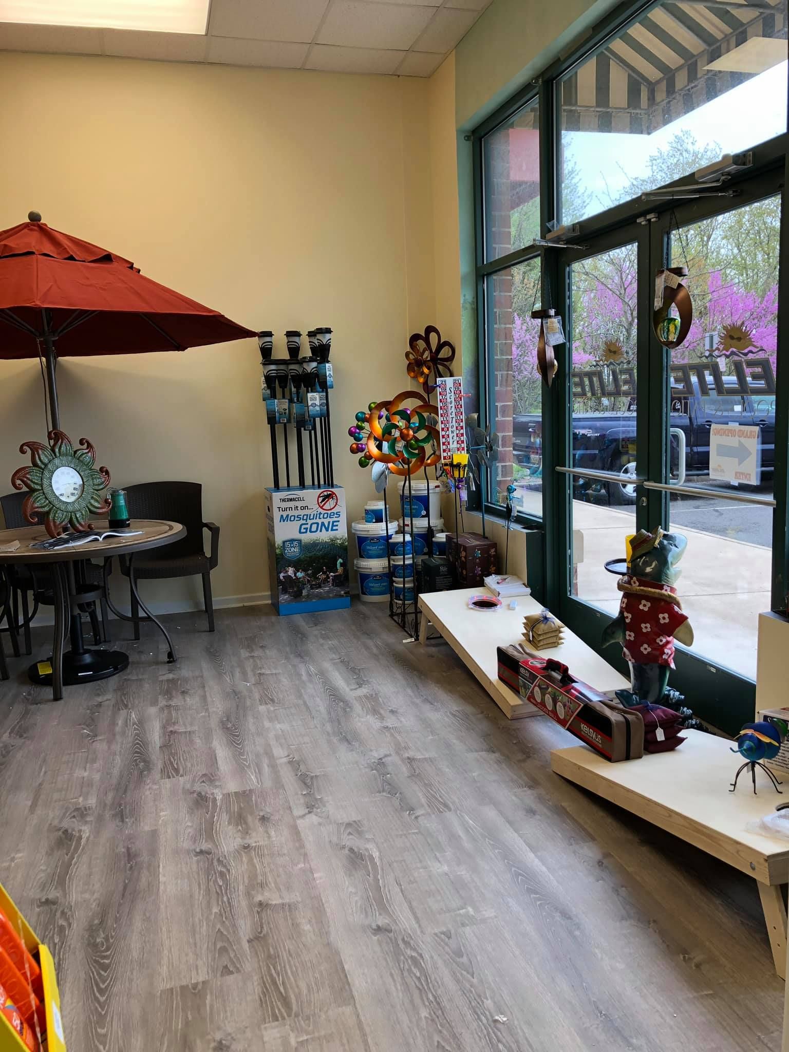 Interior shop with window display and merchandise; outdoor seating with umbrella.