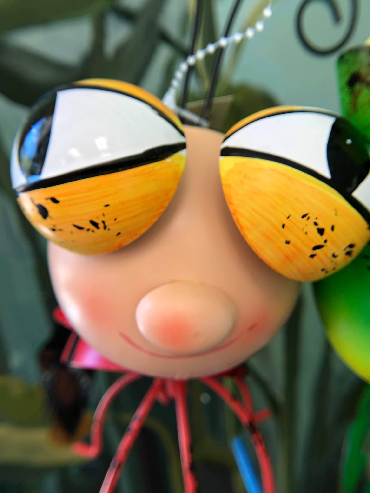 Close-up of a whimsical bug with large, yellow-rimmed eyes, rosy cheeks, and red legs.