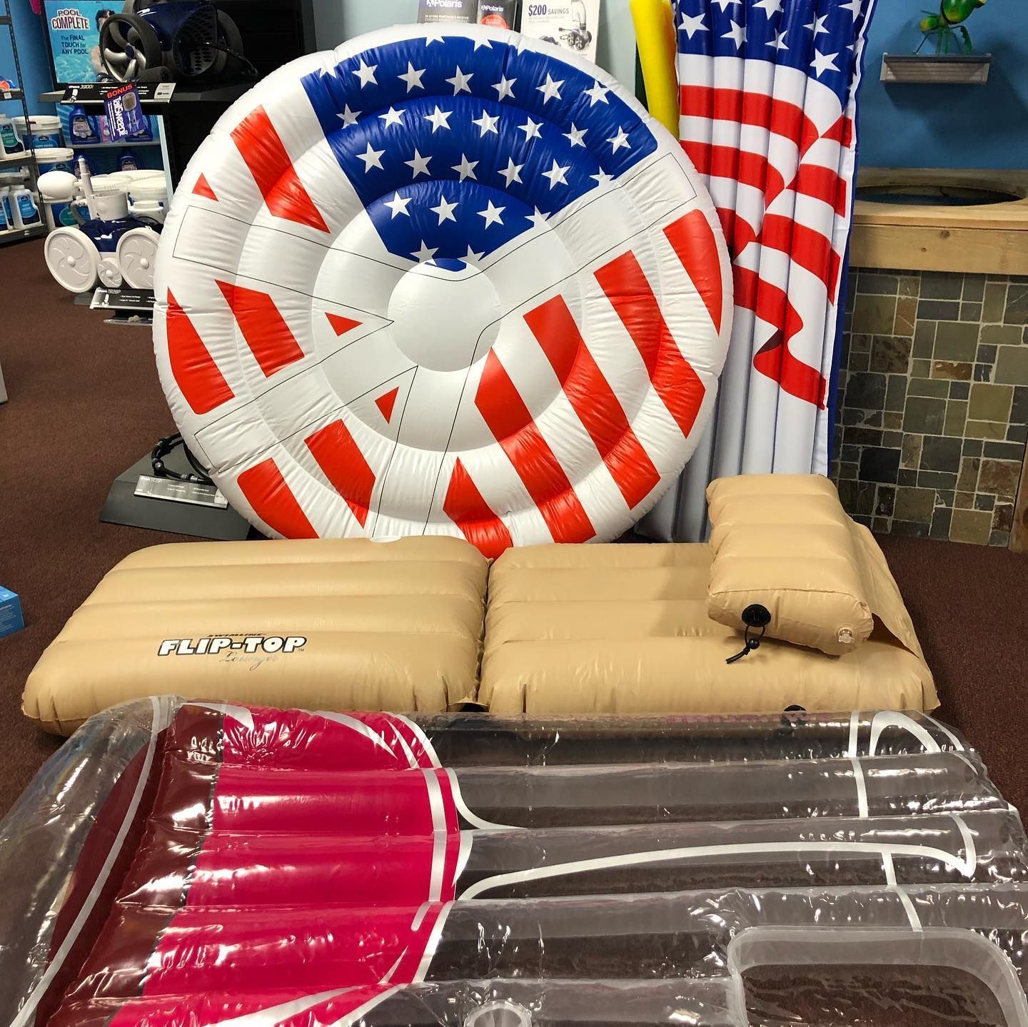 Pool floats with an American flag, tan and clear designs on display in a store.
