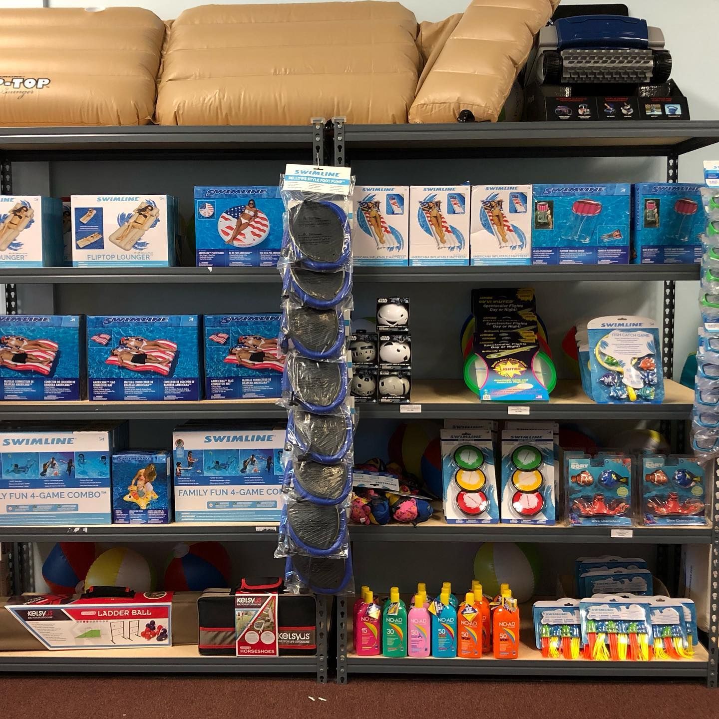 Shelves stocked with pool floats, inflatables, and beach toys in a store.