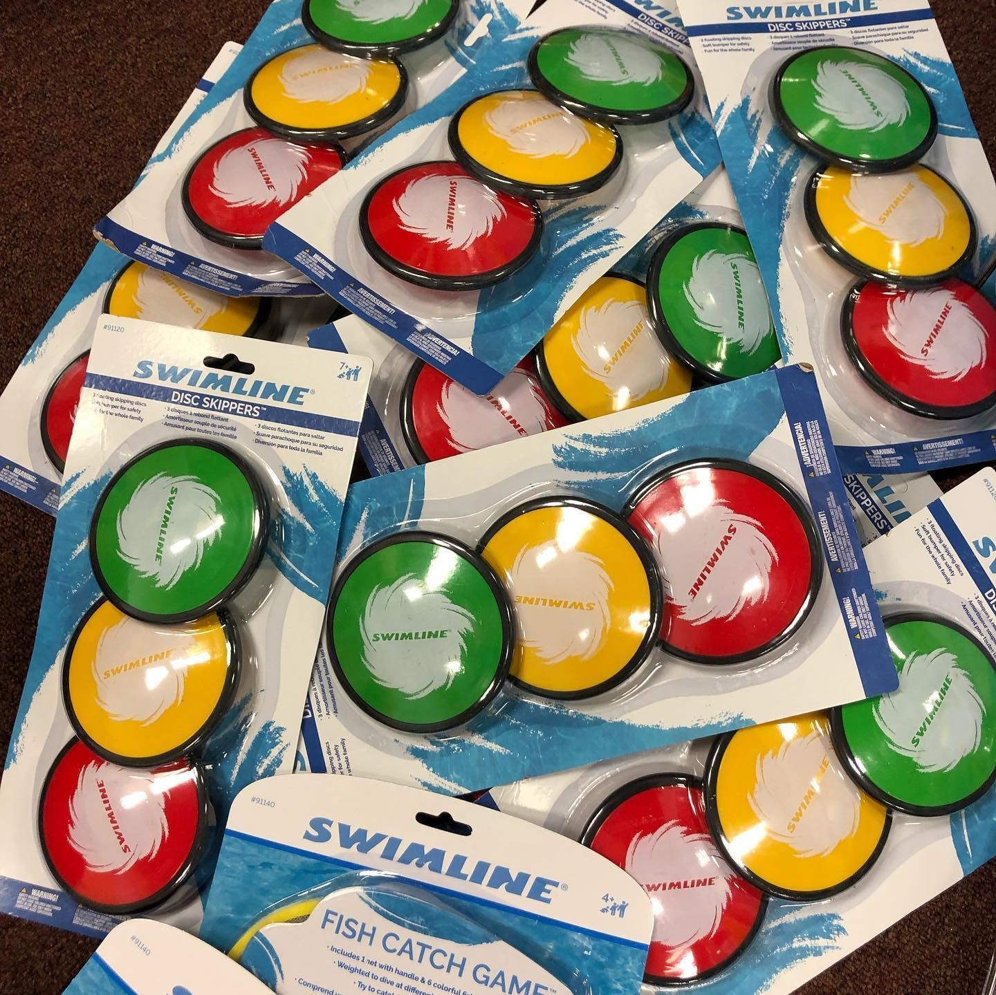 Stacks of Swimline Fish Catch Games, featuring red, yellow, and green circular discs in plastic packaging.