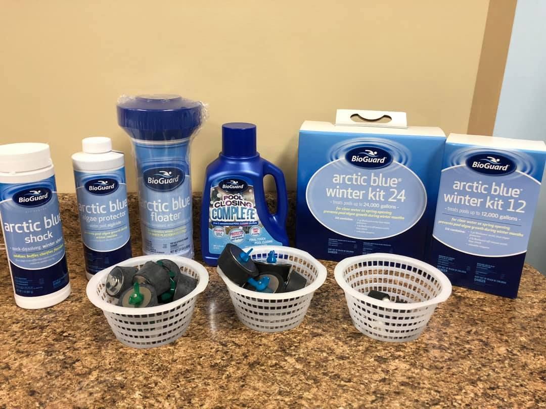 Pool winterization supplies, including chemicals and kits, arranged on a countertop.
