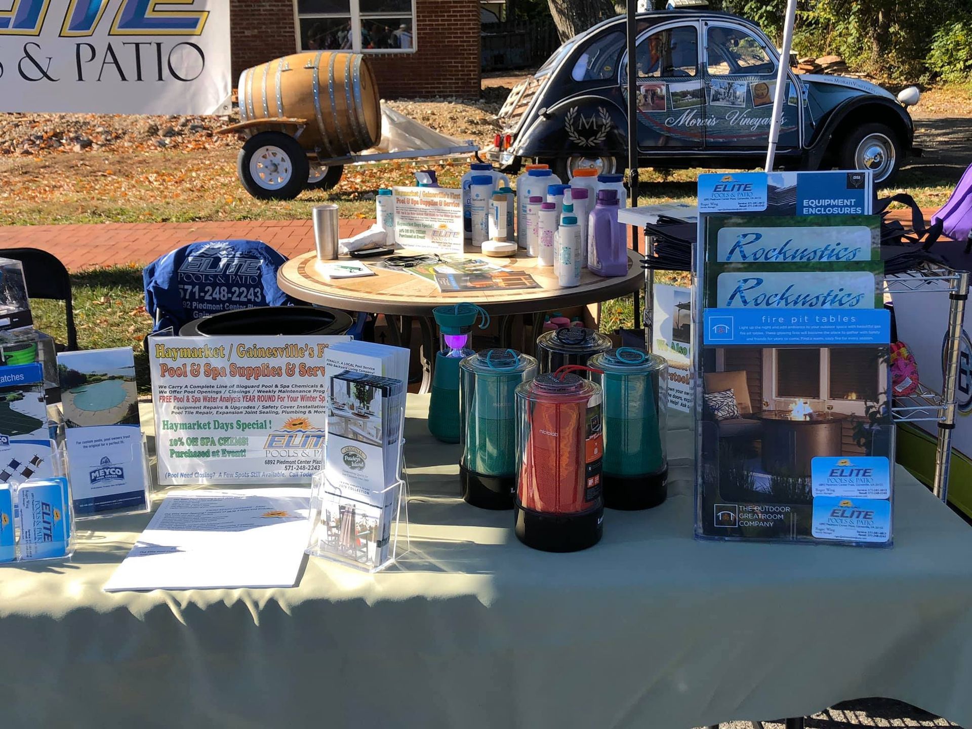 Outdoor booth with products and information displays. A car with artwork is in the background.