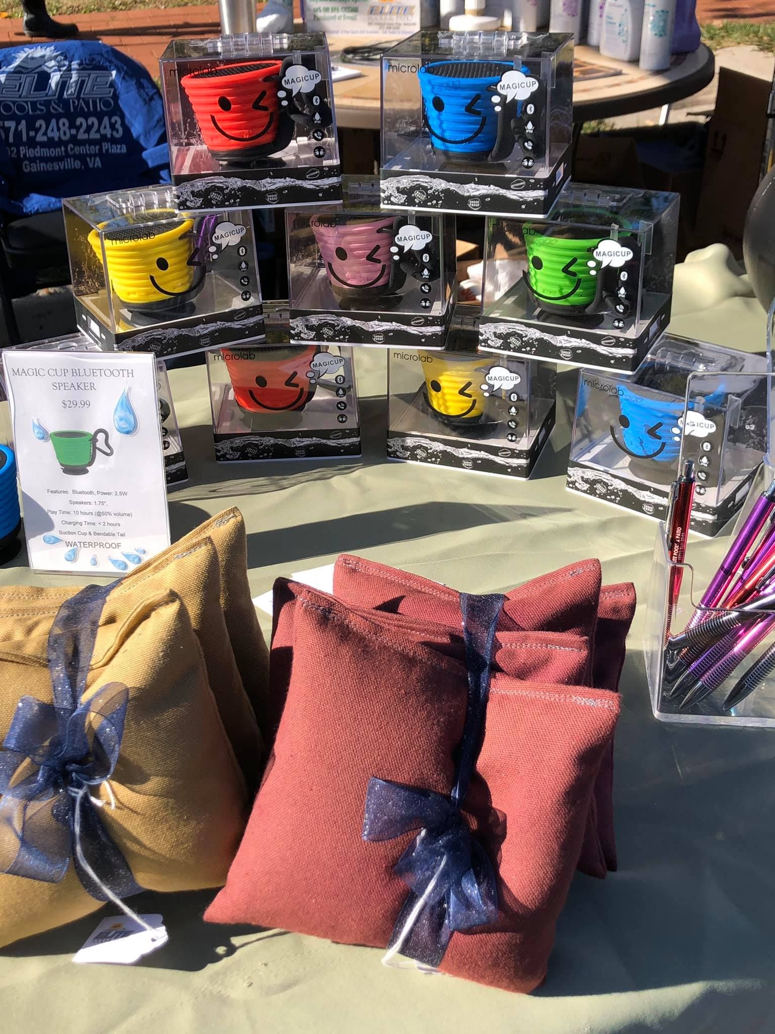 Booth with smiling cup planters in clear boxes and gift-wrapped pillows, outdoor setting.