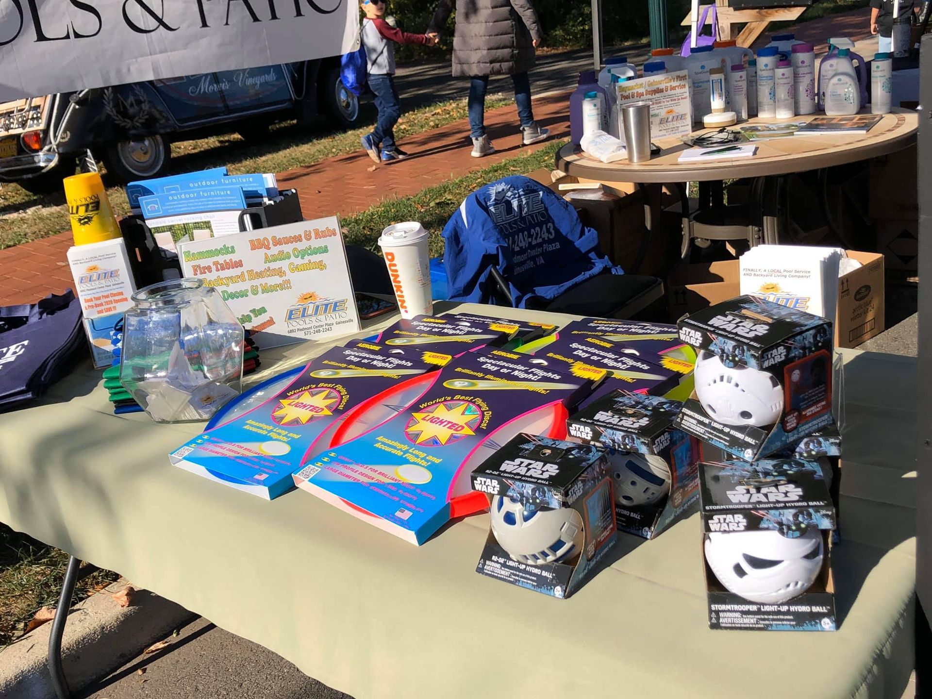 A table with Star Wars merchandise, sunscreen, and cups at an outdoor vendor booth.