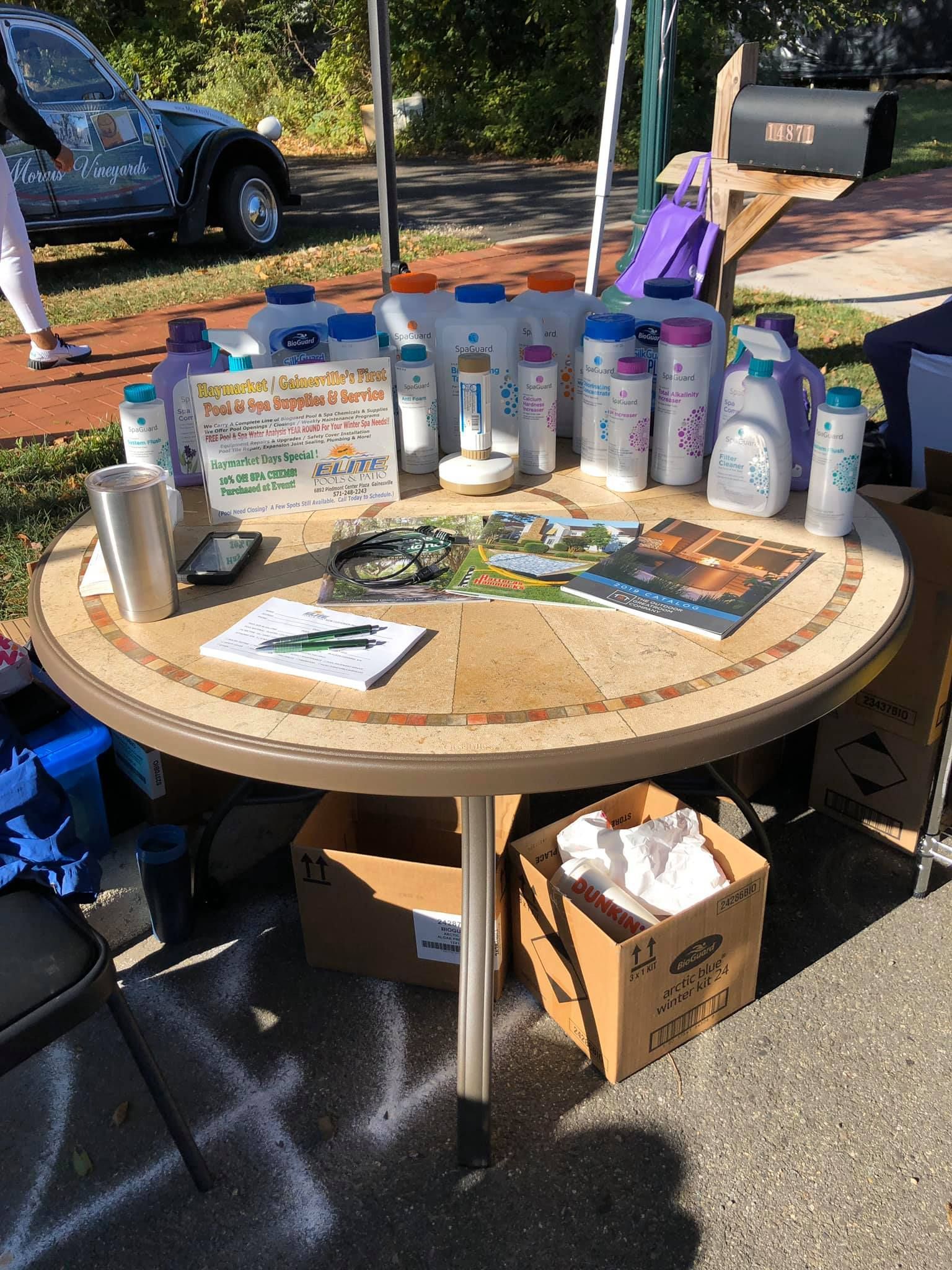 Round table with cleaning products for sale at an outdoor event.