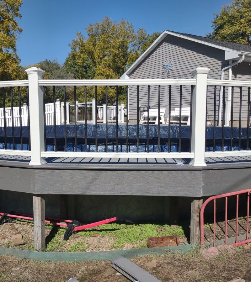 A deck with a white railing in front of a house