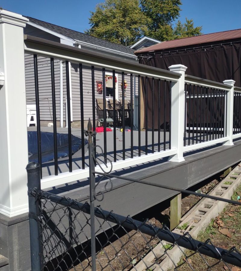 A deck with a white railing and a chain link fence