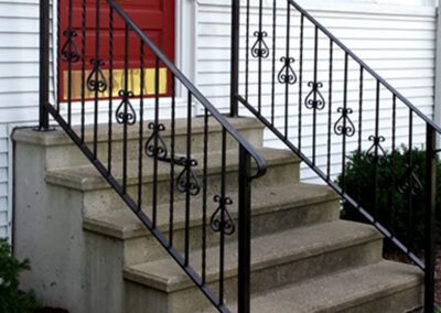 A set of stairs with a wrought iron railing and a red door