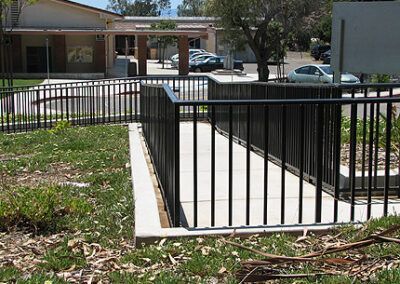A metal fence surrounds a ramp leading to a building