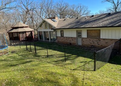 A house with a fence around it and a gazebo in the backyard.