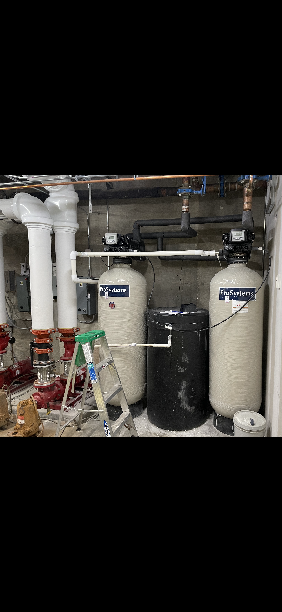 A man wearing a hard hat and safety glasses is working on a water filter.