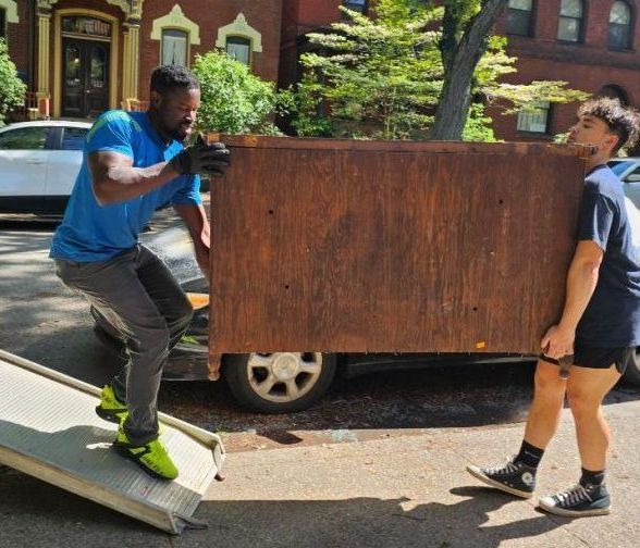 Two people are carrying a large wooden box on a ramp.