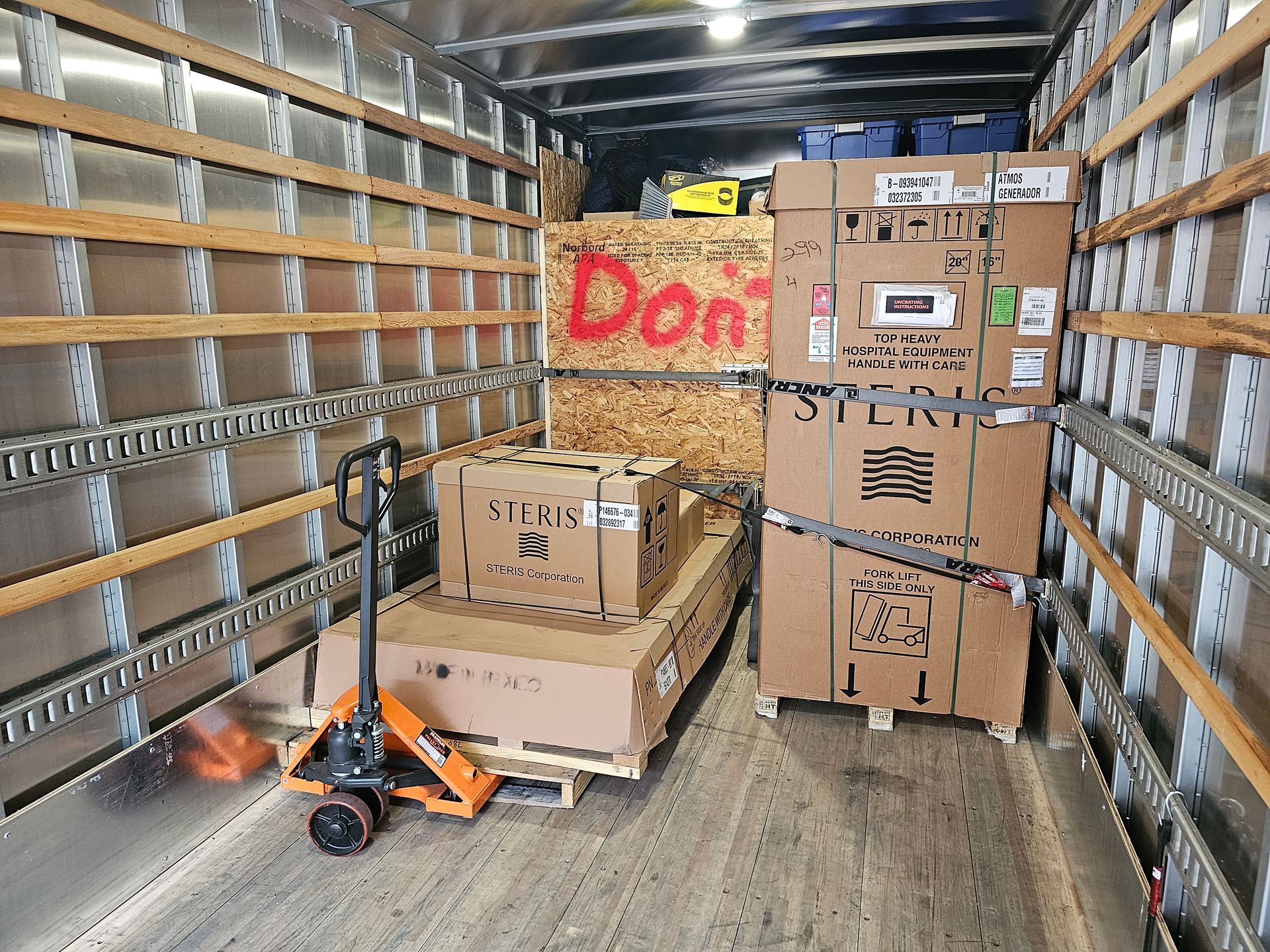 The inside of a truck filled with boxes and a pallet jack.