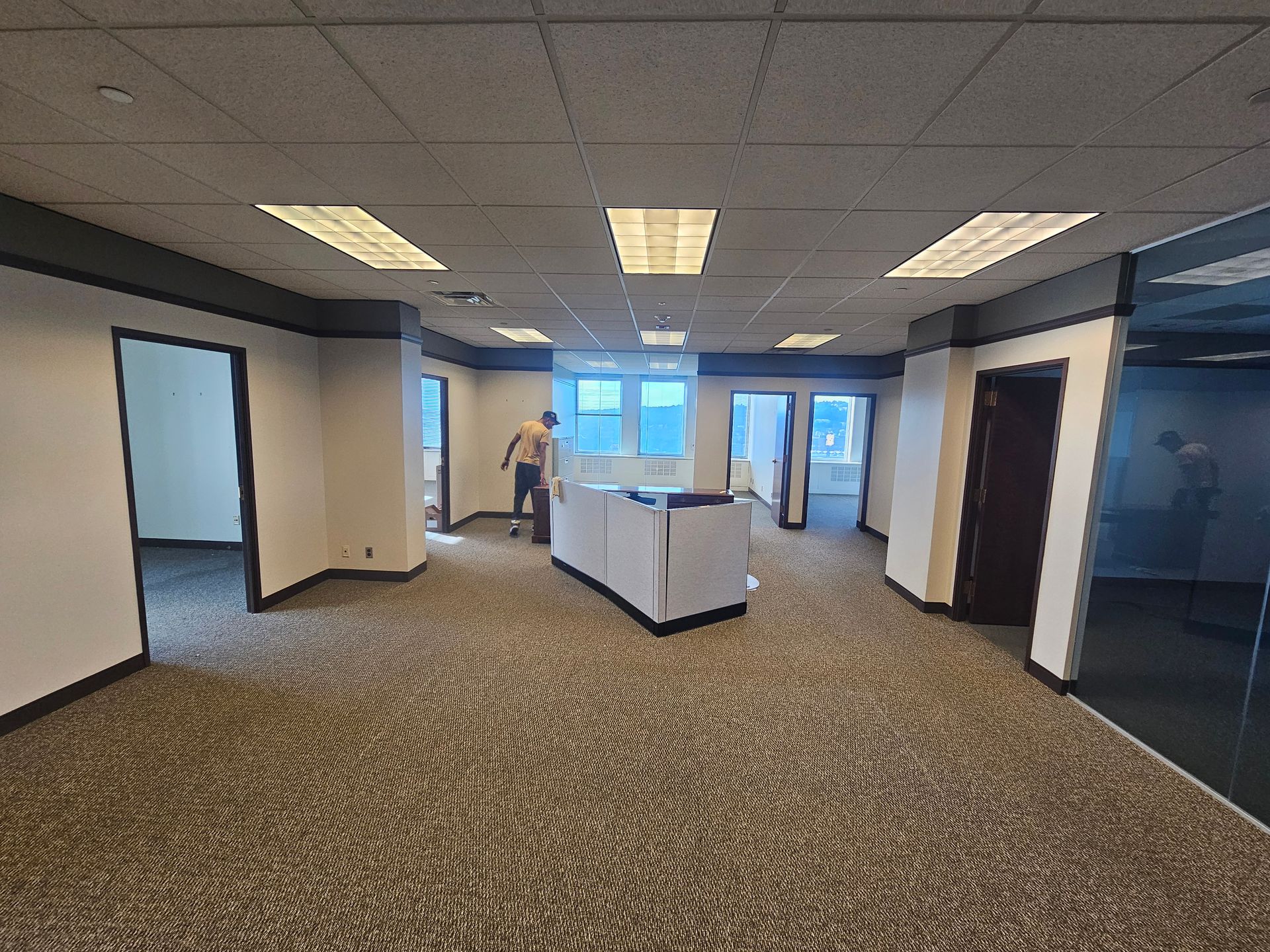 A man is standing in an empty office with a carpeted floor.