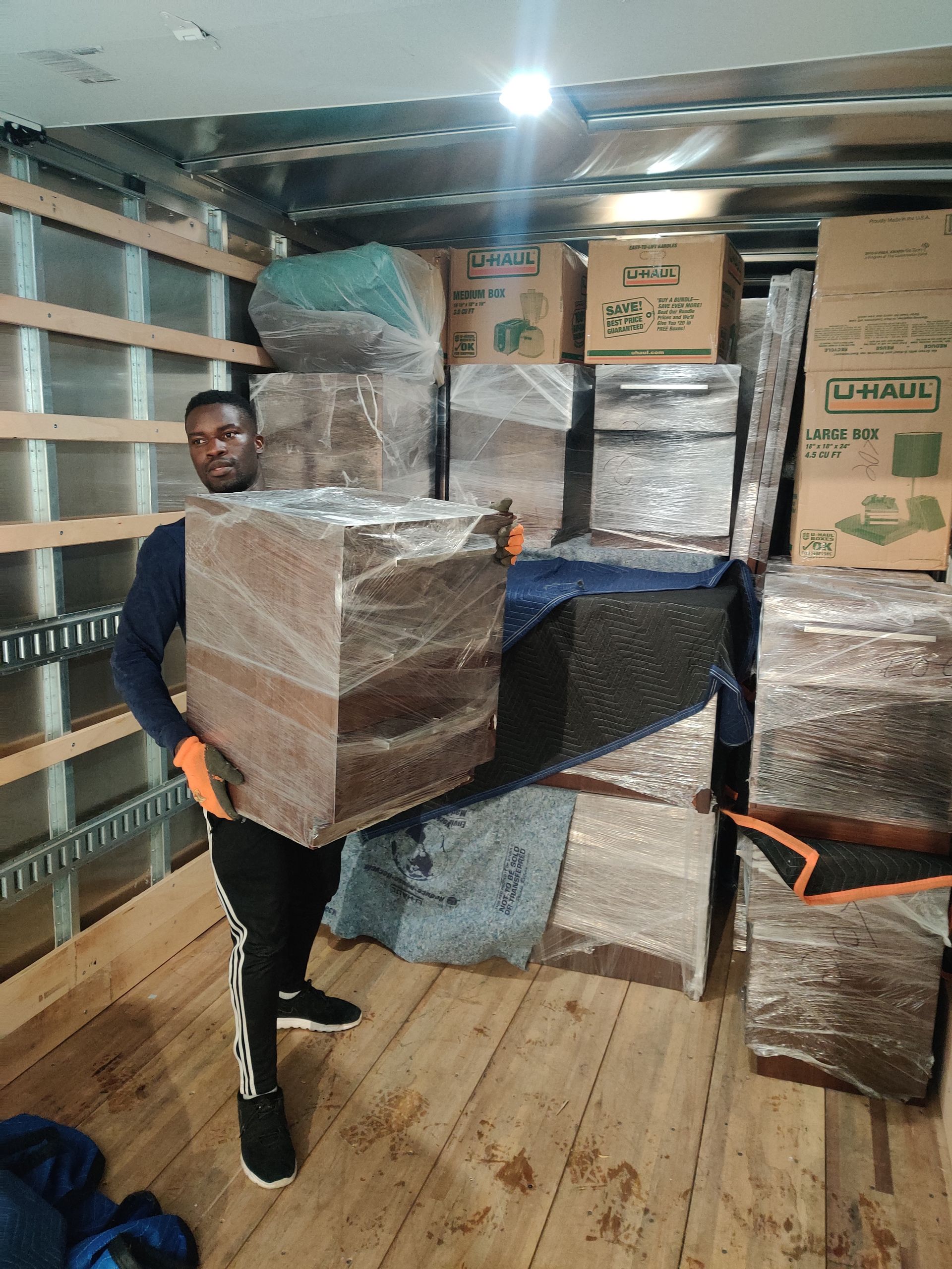 Interior of a cluttered storage unit: boxes, furniture, clothing, and other items filling the space.