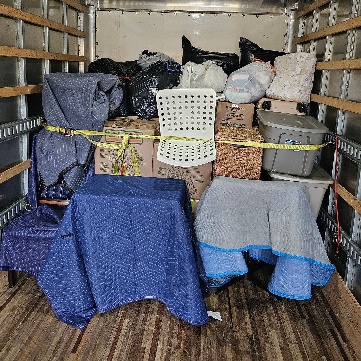 The back of a moving truck filled with boxes and chairs.