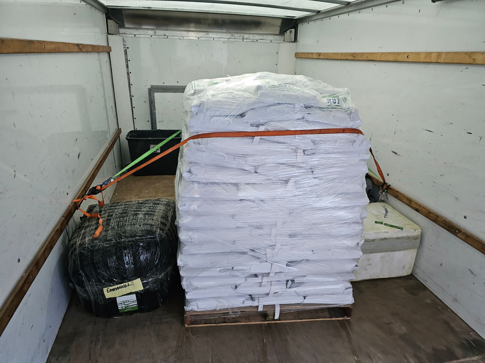 A large stack of white bags on a wooden pallet in the back of a truck