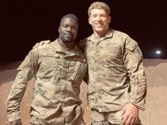 Two soldiers in camouflage uniforms standing together at night in a desert setting