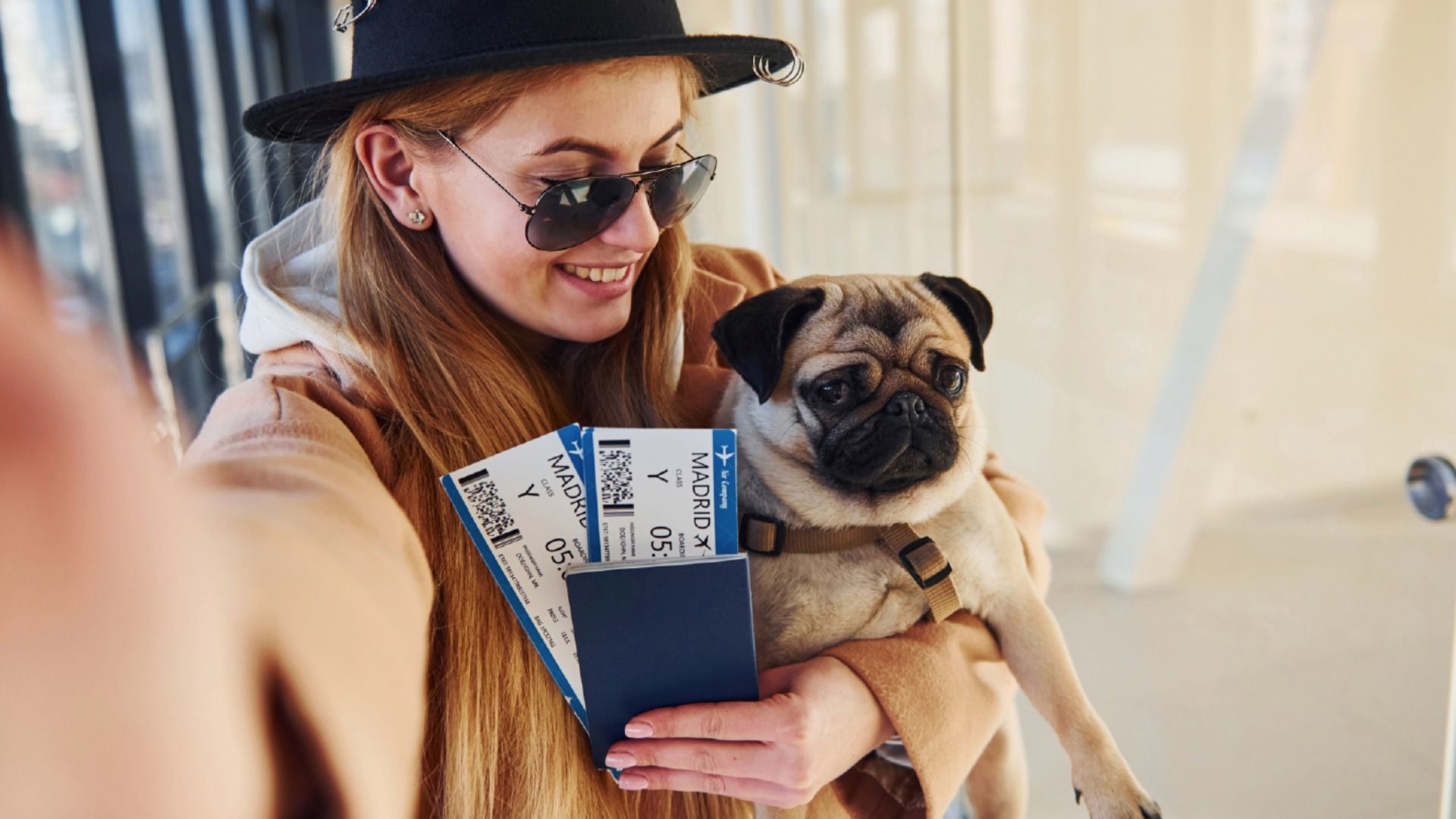 寵物移居客戶回饋情境意象－飼主與巴哥犬於機場自拍，呈現完成出國準備後與毛孩同行的喜悅時刻。