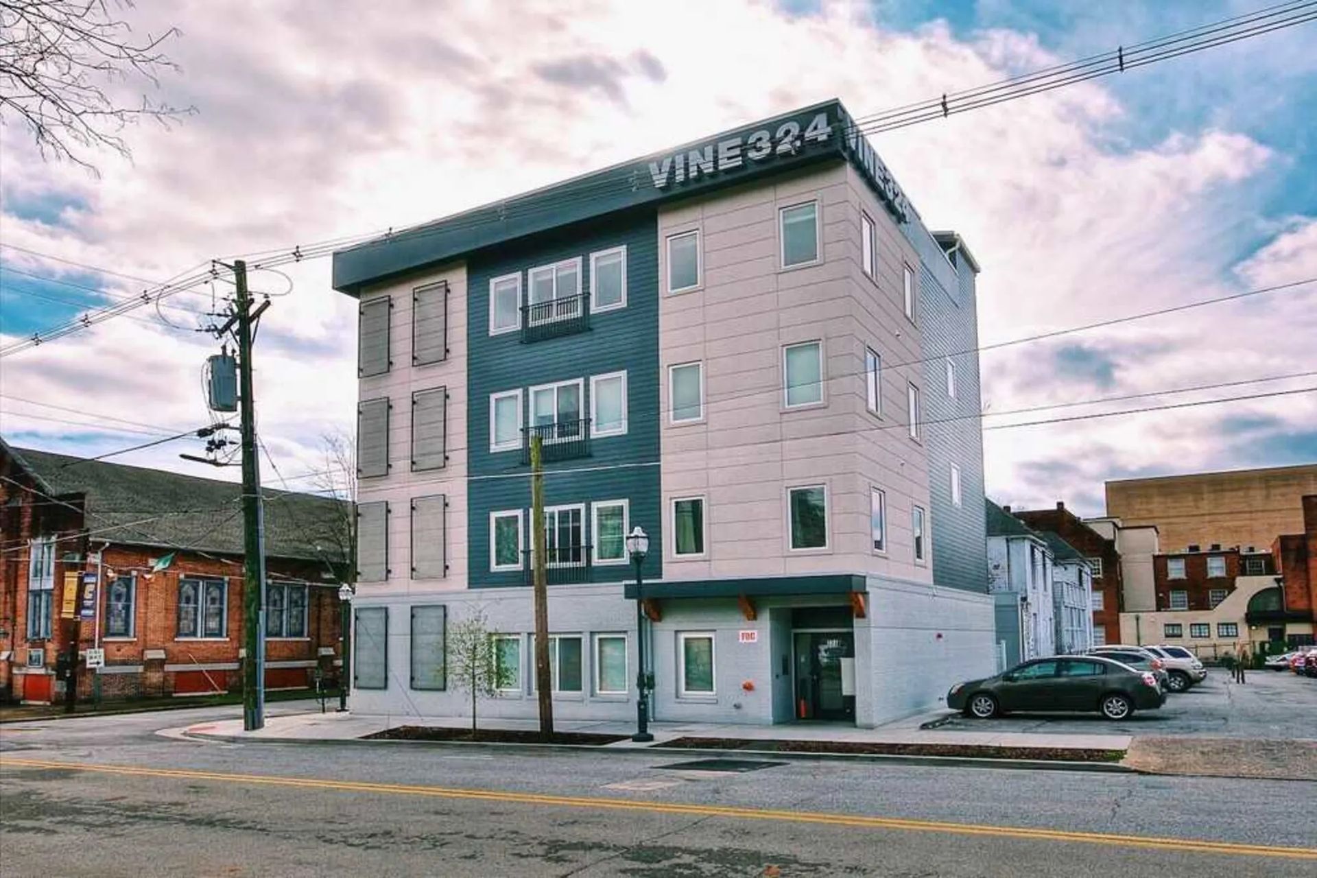 A large building with a lot of windows is sitting on the corner of a street.