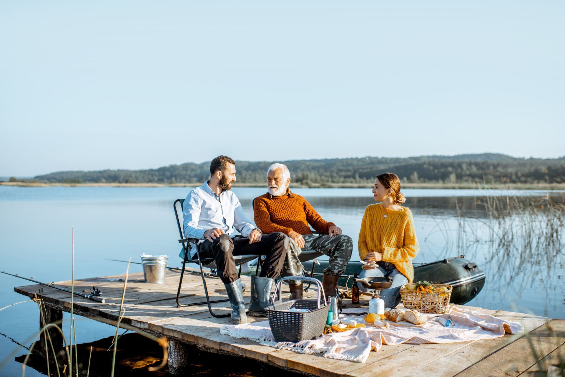 A group of people are sitting on a dock near a lake.