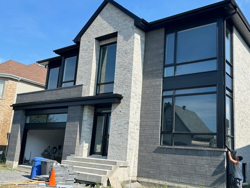 Un homme se tient devant une grande maison avec beaucoup de fenêtres.
