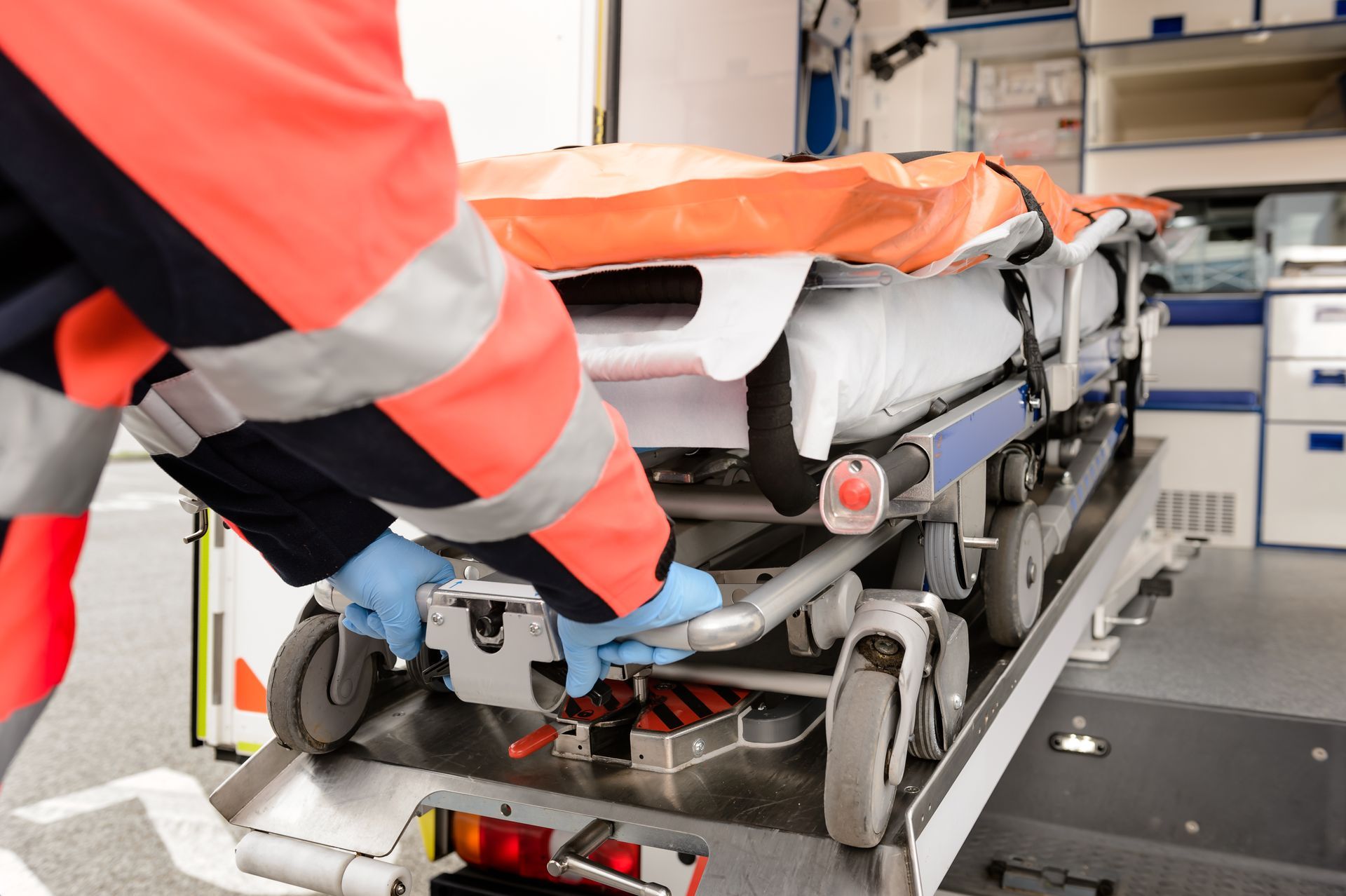 Paramedics loading a patient on a stretcher into an ambulance