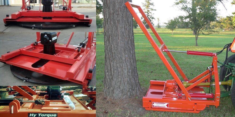 An orange brush cutter attached to a tractor is set against a tree.
