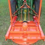Orange rotary mower attached to a green tractor; close-up view.