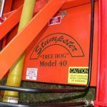 Orange "Stumpster" tree stump grinder, Model 40, with a caution label.
