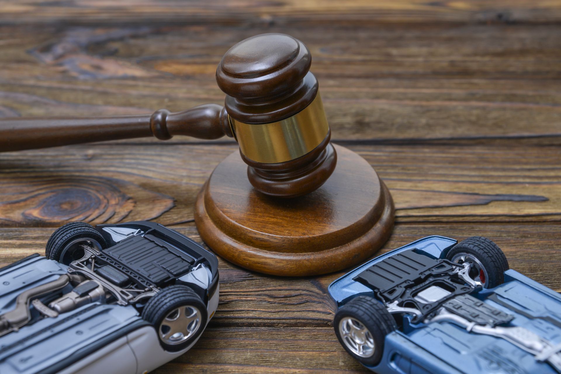 A gavel and overturned toy cars symbolizing a car accident lawyer's office.