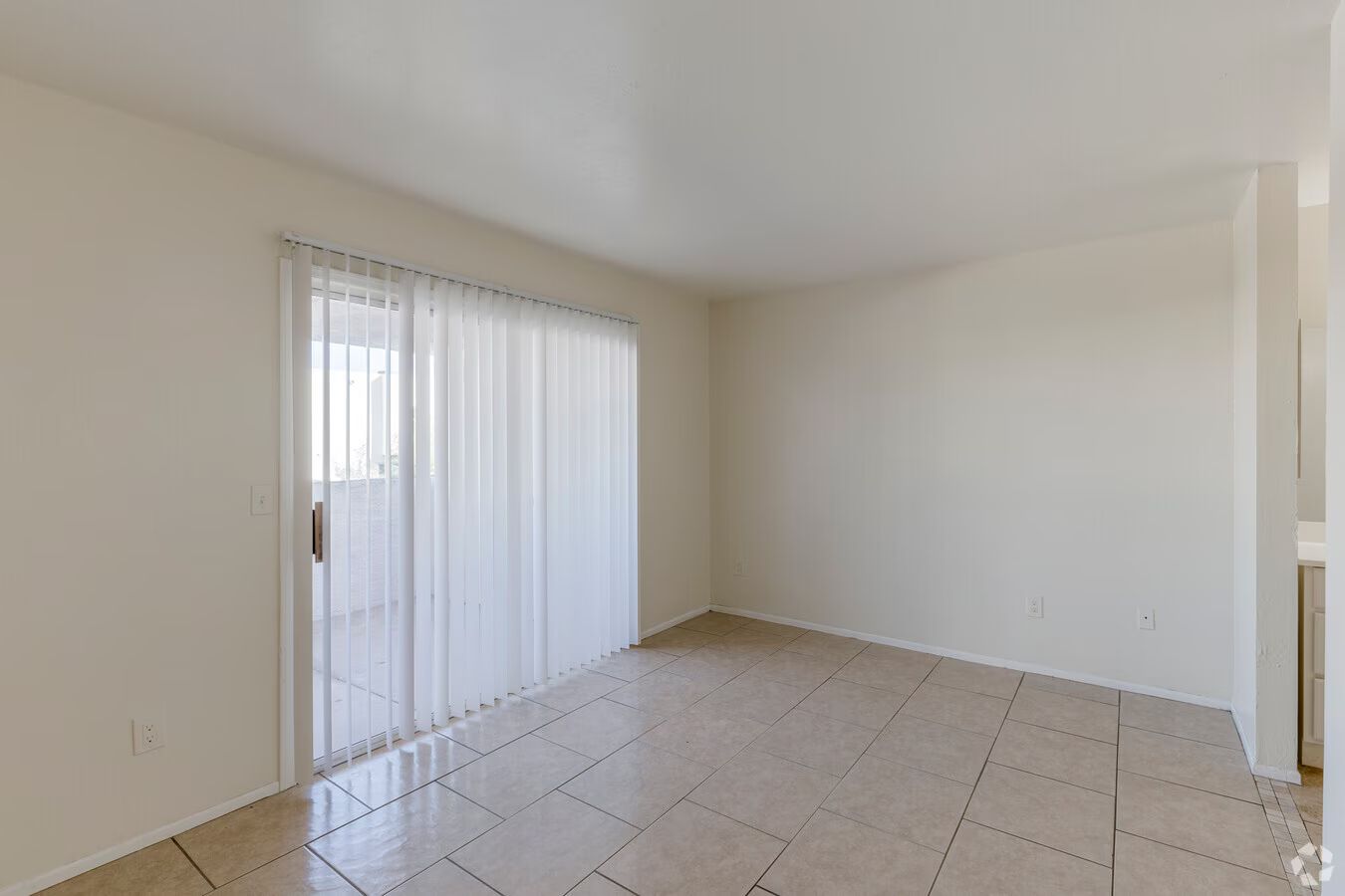 Photo of a living room with plenty of natural light and a sliding door leading to a patio