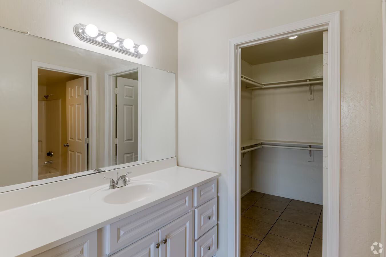 Photo of a bathroom sink with a wide cabinet and a walk-in closet in the background