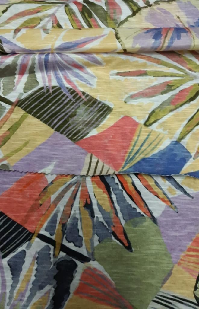 Una vista de cerca de una tela que presenta un patrón atrevido y superpuesto de hojas tropicales 