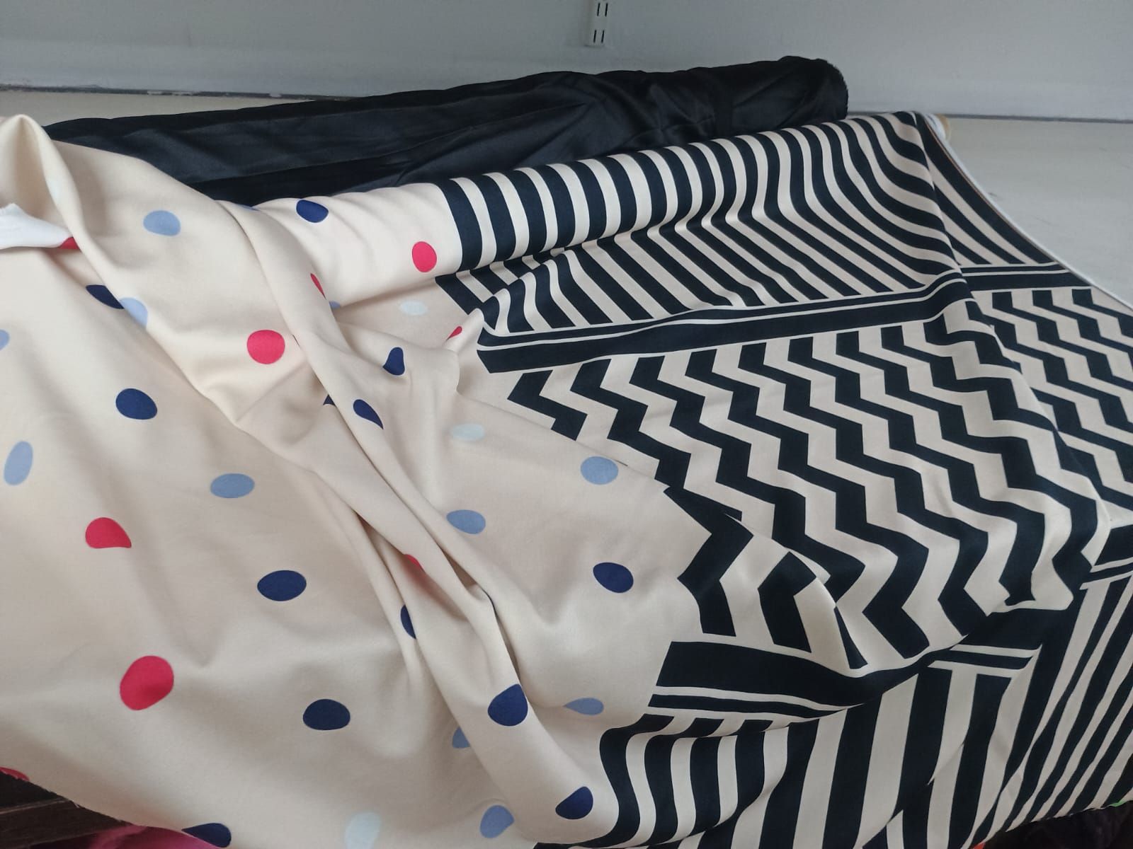 Una tela con un estampado de lunares en un lado y un estampado de rayas chevron en blanco y negro en el otro.
