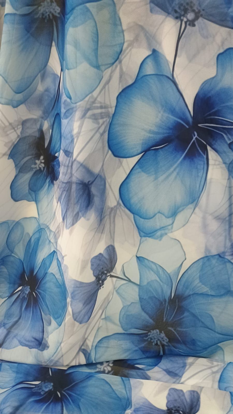 Un patrón de flores grandes de color azul translúcido en distintos tonos, dispuestas sobre un fondo blanco.