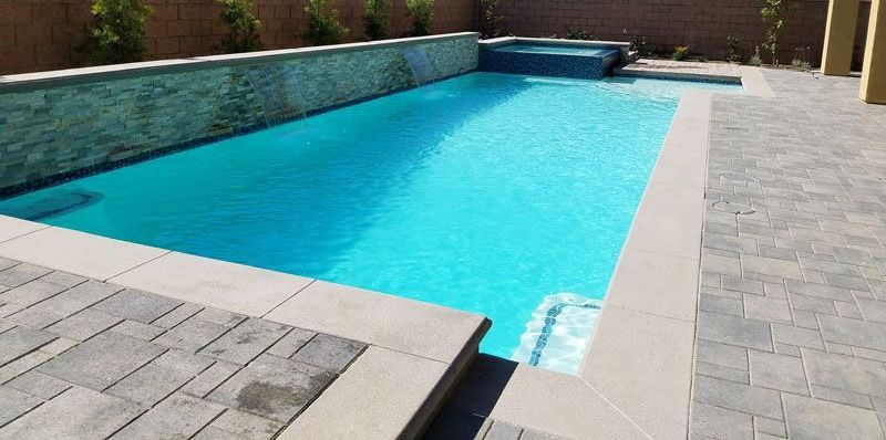 There is a large swimming pool in the backyard of a house.