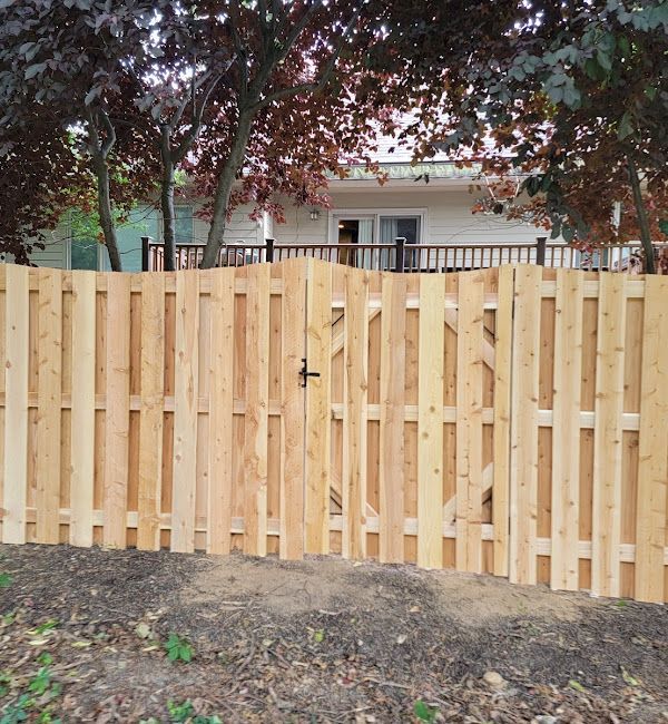 A wooden fence with a gate in front of a house