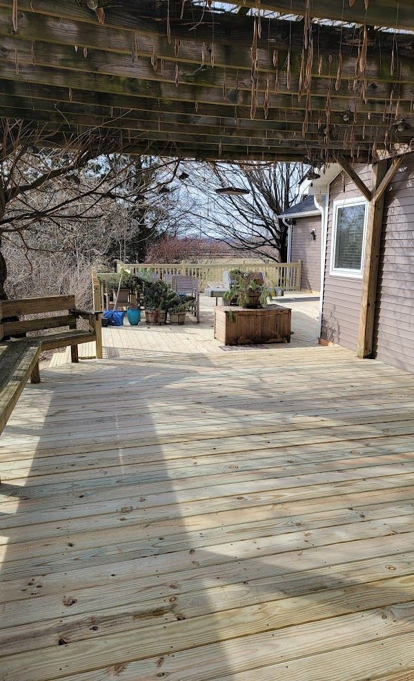 A wooden deck with a pergola over it and a bench.