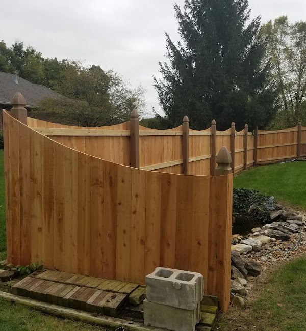 A wooden fence is surrounded by grass and trees