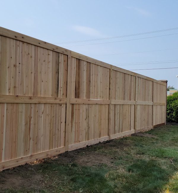 A wooden fence is sitting in the middle of a lush green field.